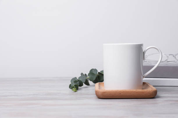 istock White ceramic mug, stack of books and eucalyptus branch on white wooden table, space for text 1653396732