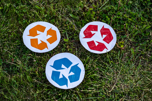 recycling symbols on the grass, blue, red and orange colors