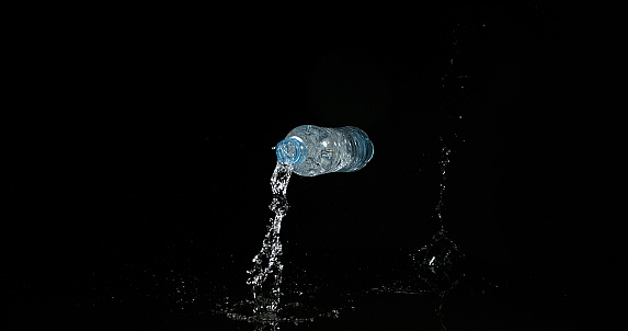 Plastic Bottle of Water falling and Splashing against Black Background