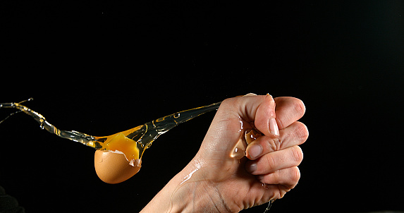 Hand of woman with a Chicken Egg against Black Background