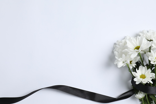 Beautiful chrysanthemum flowers and black ribbon on white background, top view with space for text. Funeral symbols