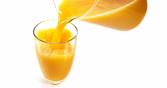 Orange slices falling into the glass of orange juice splashing  orange juice crown. Conceptual drink background.