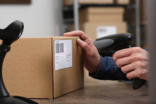 istock Seller with scanner reading parcel barcode at table in office, closeup. Online store 1653471593