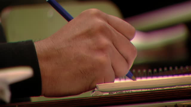 Hand of a Male Student Writing on Spiral Notebook at Class. Close Up.