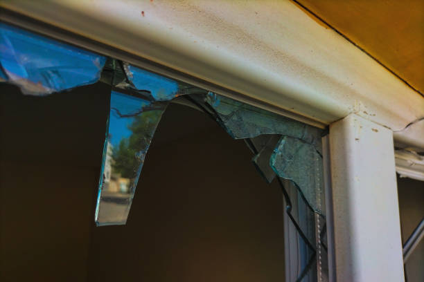 разбитое пластиковое окно с оставшимися осколками, через которое проникли воры и похитили ценные вещи. понятие безопасности, частная собст - burglary broken window door стоковые фото и изображения