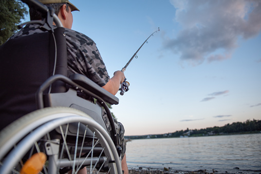 A disabled person in a wheelchair is fishing