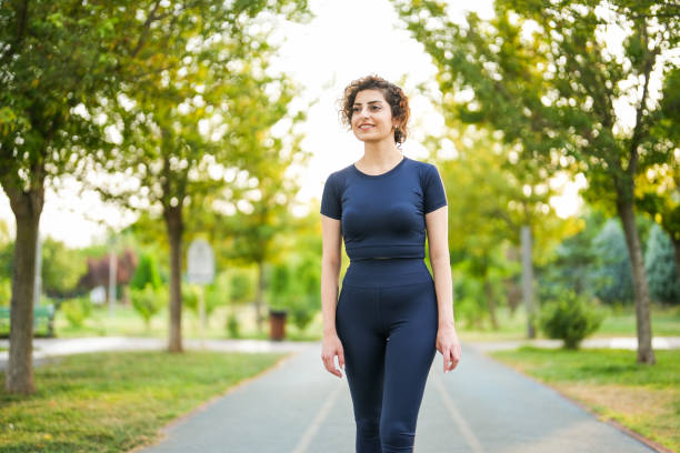 young woman with curly hair walking with backpack in the park young woman with curly hair walking with backpack in the park dişiler stock pictures, royalty-free photos & images