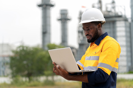 Accomplished African American engineer who exemplifies the future of remote power plant control and capacity optimization. Operates a laptop computer, a powerful tool for managing the intricate systems of a modern power plant. Minimize waste and embrace a Zero Waste future