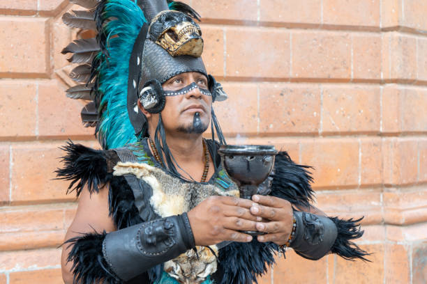 chaman concentré utilisant un calice ou un calice, danseur aztèque avec coiffe à plumes et crânes sur son costume, artiste traditionnel mexicain de culture hispanique - asian tribal culture photos photos et images de collection