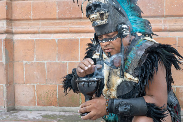 chaman concentré sentant la fumée d’un calice ou d’un calice rituel, danseur aztèque avec coiffe à plumes et crânes sur son costume, artiste traditionnel mexicain de culture hispanique - asian tribal culture photos photos et images de collection