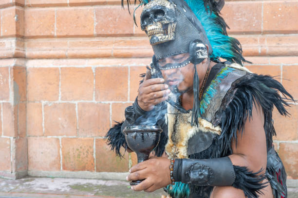 istock concentrated shaman smelling smoke from a calyx or ritual chalice, aztec dancer with feathered headdress and skulls on his costume, hispanic culture mexican traditional performer 1653908731