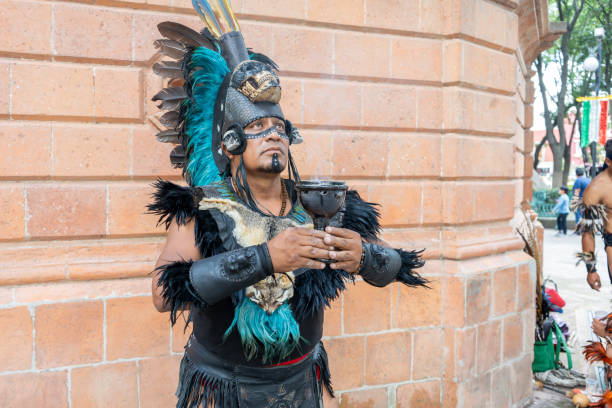 konzentrierter schamane mit kelch o kelch, aztekischer tänzer mit gefiedertem kopfschmuck und totenköpfen auf seinem kostüm, hispanische kultur mexikanischer traditioneller darsteller - north american tribal culture fotos stock-fotos und bilder