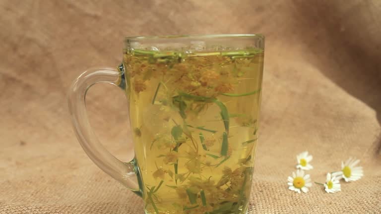 Hot water is poured into a glass mug with chamomile.