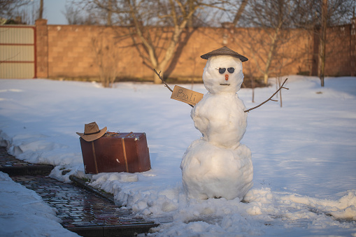 Snowman hitchhiking to Bali island in winter. Snowman catch a car by the road. Hitching a ride