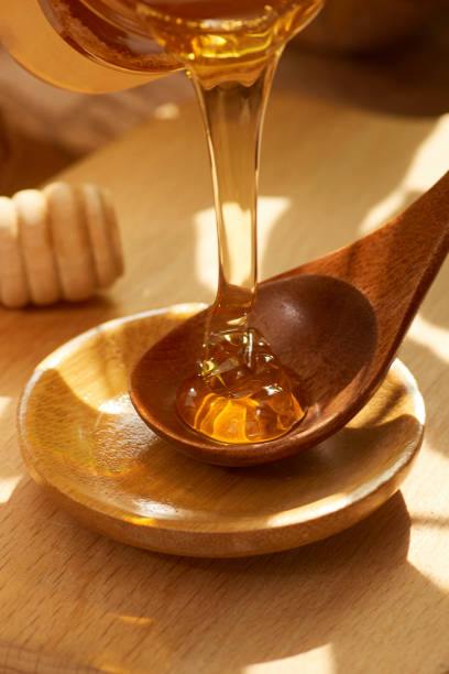 istock Tasty natural yellow golden bee honey flows in a thin stream from a spoon into a plate 1654067547