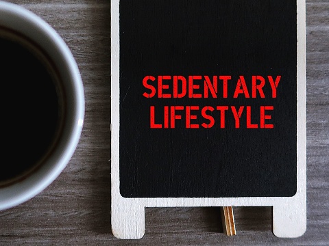 Chalkboard with handwritting text SEDENTARY LIFESTYLE , refers to people who lives sedentary lifestyle, lazy and inactive couch potato who watch TV and eats junk food all the time