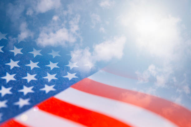 American flag against a blue sky with clouds and sunlight, collage, mixed media. stock photo