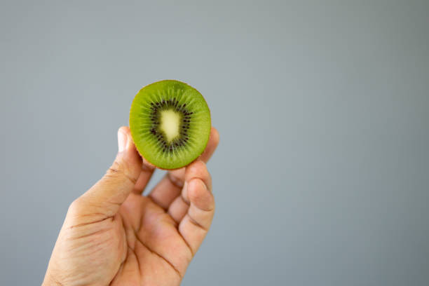 istock Close up hand holding kiwi fruit 1654144791