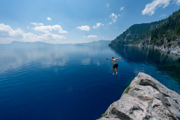 istock Man jumping into Crater Lake on sunny summer day 1654167939
