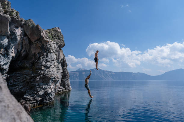 istock Two men jumping off cliff into lake 1654168072