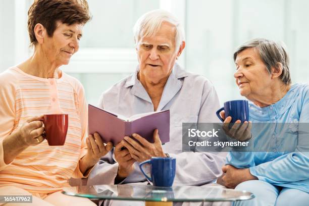 Senior Personas Disfrutando Mientras Lee Un Libro Foto de stock y más banco de imágenes de Amistad - Amistad, Mesa - Mueble, Mujeres mayores