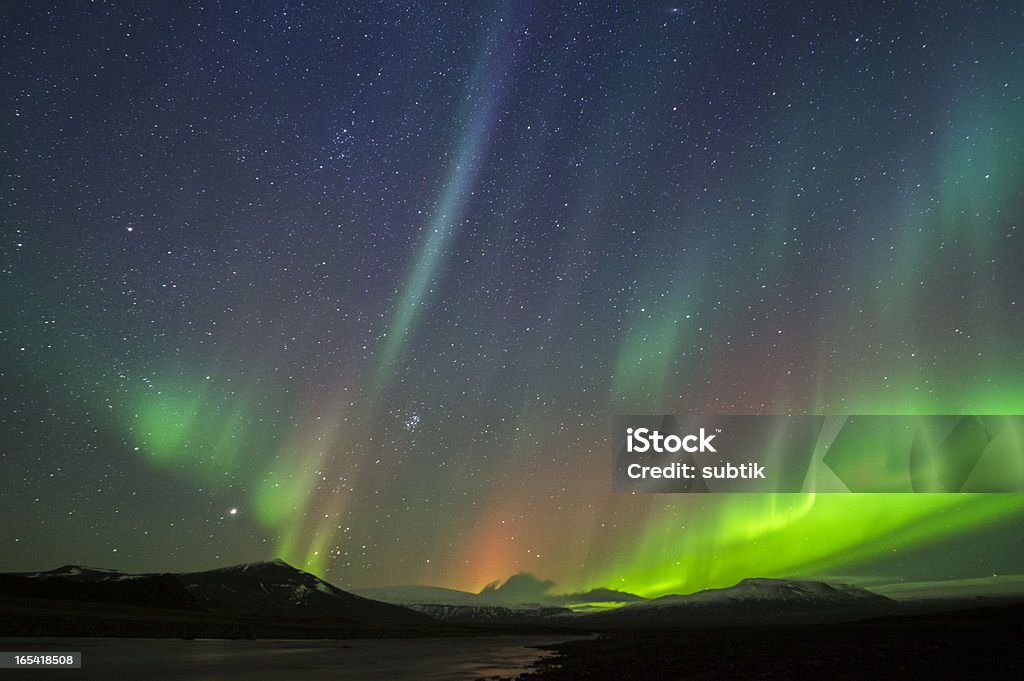 Northern lights against starry sky and silhouette mountains aurora borealis on iceland,  some ISO-noise Shiny Stock Photo