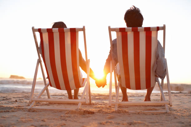 istock Rear view of couple in deck chairs on beach 165419109
