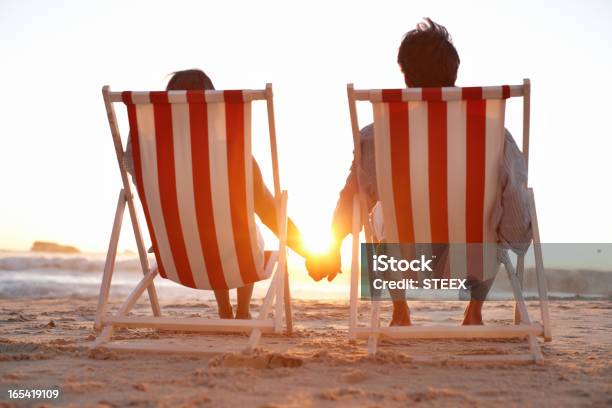 Foto de Vista Traseira De Um Casal Em Espreguiçadeiras Na Praia e mais fotos de stock de Casal de Meia Idade