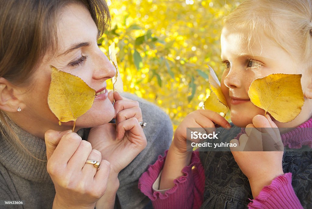 Madre e figlia, giocando con foglie di autunno giallo - Foto stock royalty-free di 4-5 anni