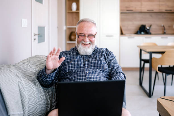 istock Mature man using laptop for online conference in his home 1654285275