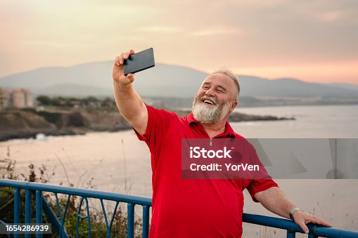 istock Smiling mature man taking a selfie while on a summer vacation 1654286939