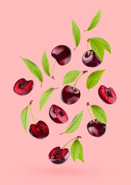 istock Juicy red cherry with green leaves as flow fly or fall as art composition. Whole, half pieces fruits on pastel pink background with shadow. Ripe raw fruits for advertising, design, label product. 1654287992