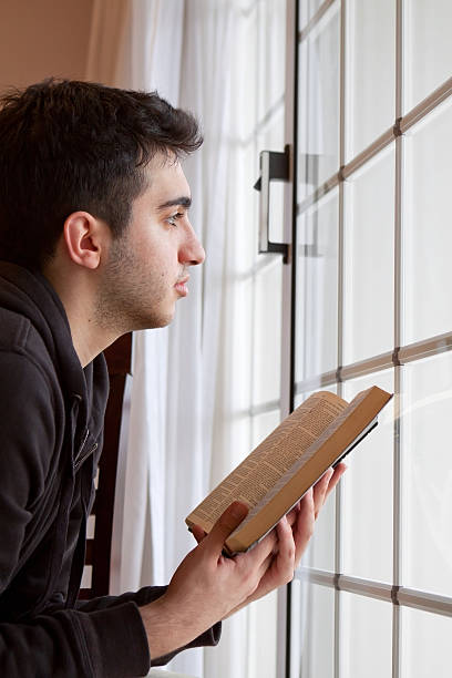istock Man Holding Bible Looking Out Window 165433142