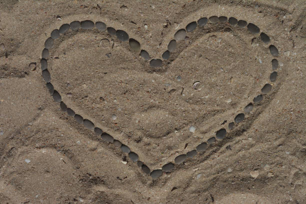 istock Heart of pebbles in the sand 1654350124