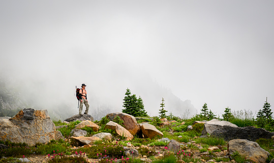 Man standing on top of rocks at Skyline Loop Trail. Mt Rainier National Park in the fog.Washington State.