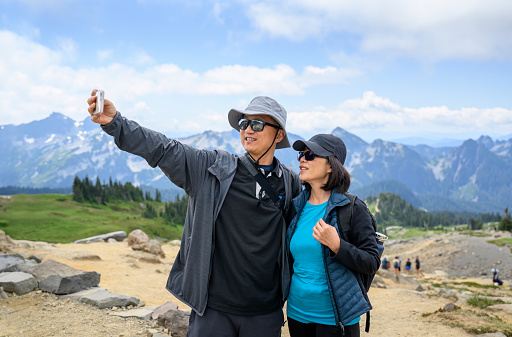 Couple taking selfie photo using smartphone at Skyline Loop Trail. Mt Rainier National Park. Washington State