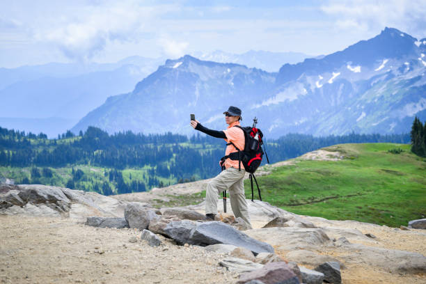 Tourist taking selfie photos using smartphone at Skyline Loop Trail. Mt Rainier National Park. Washington State.
