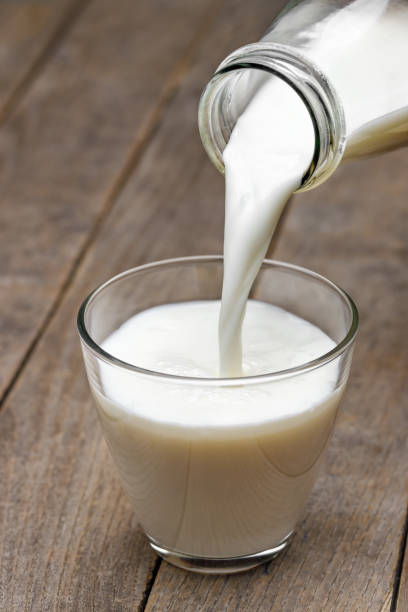 istock milk pouring in glass from bottle on table 1654453581