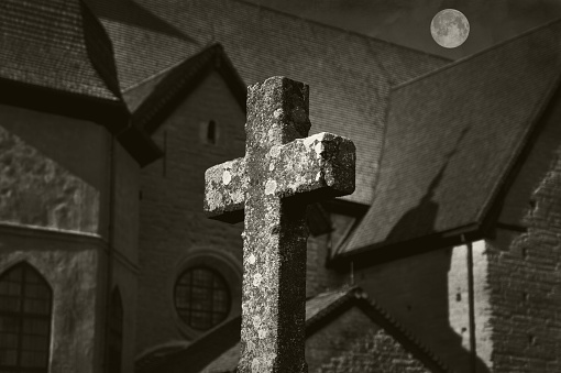 Cross in front of a church with full moon in black and white.