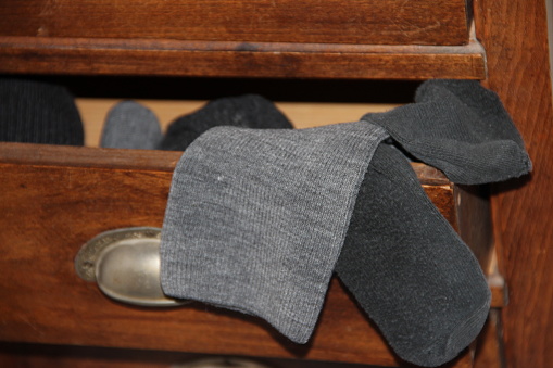 an open wooden drawer with grey socks sticking out