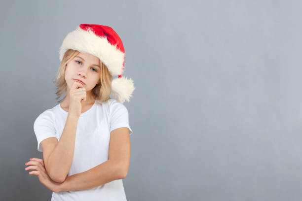 Young girl Santa thinking on light blue background