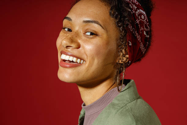 istock Close up of charming woman looks camera with smile while posing on red studio background 1654523186