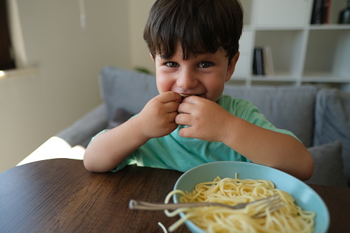 Cute child eating spaghetti.