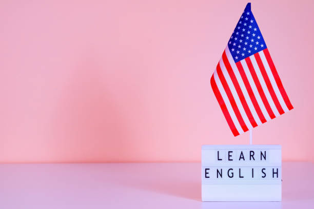 istock USA flag and text learn English on a pink wall background. 1654524182