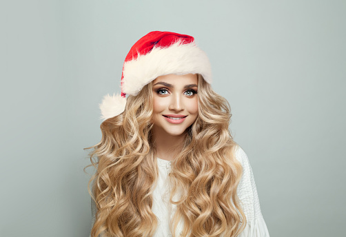 Portrait of cheerful blonde woman in Santa hat smiling on white banner background, Christmas model