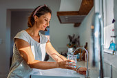 Beautiful woman filling a glass with filtered water right from the tap