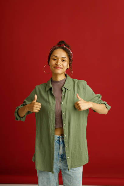 istock Happy woman showin thumbs up with smile while standing over red studio background 1654524358
