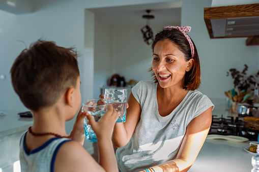 Mother and her toddler filling a glass with filtered water right from the tap