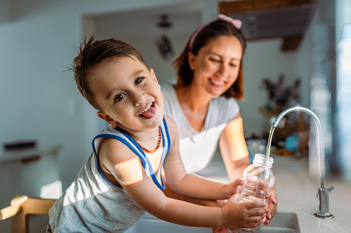Mother and her toddler filling a glass with filtered water right from the tap
