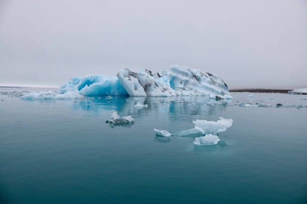 un iceberg azul en islandia. un iceberg que desemboca en la laguna de jokulsarlon, separado del frente del glaciar. - natural disaster glacier iceberg melting fotografías e imágenes de stock